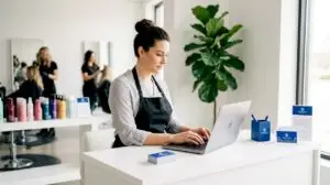 Salon manager composing client email at reception