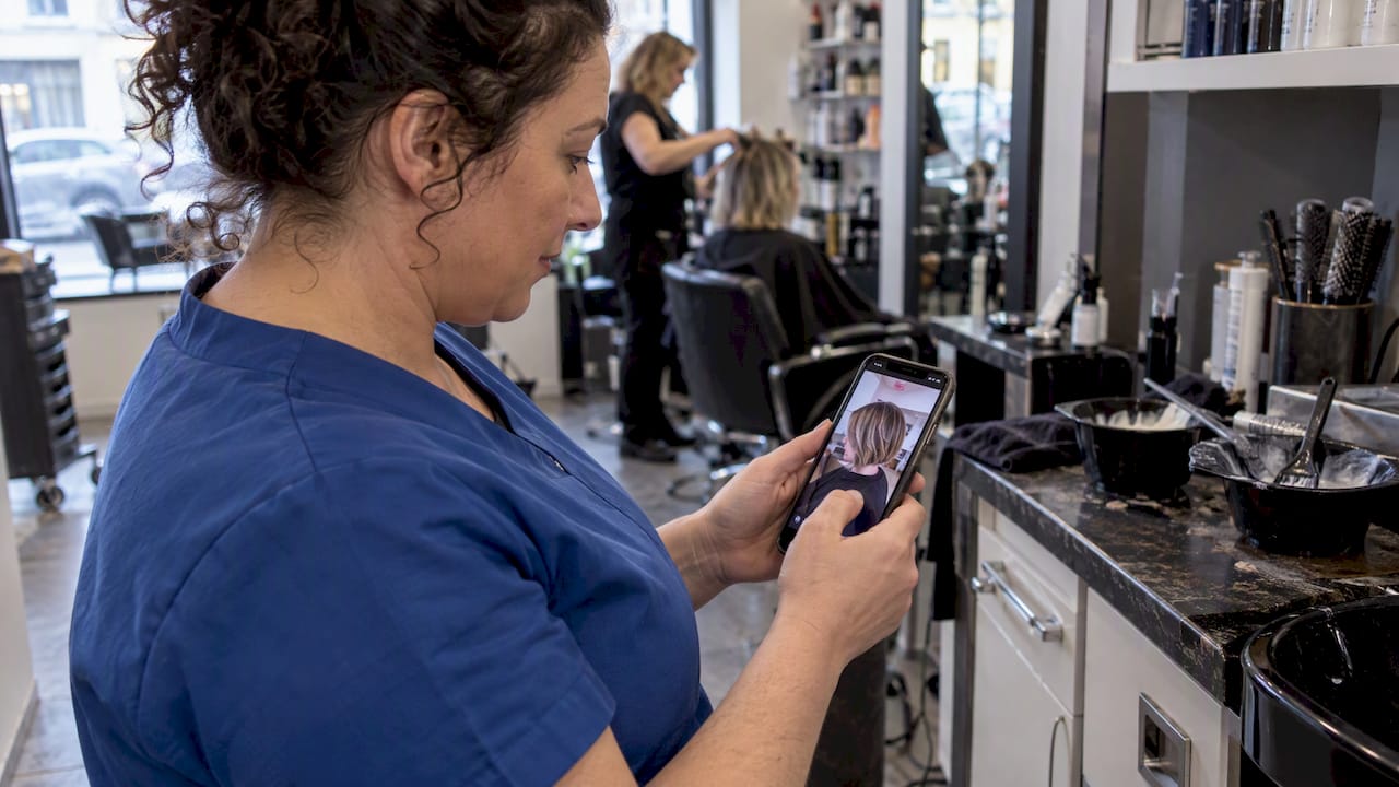 Salon owner reviewing a haircut clip on phone